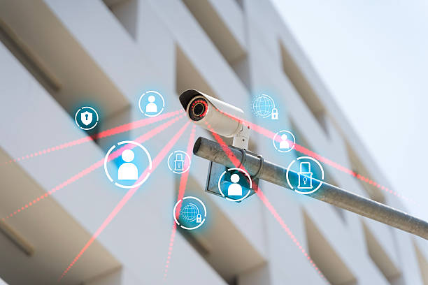 Outdoor CCTV camera monitors a building with digital security icons and network beams, representing surveillance, cybersecurity, privacy protection, monitoring systems, and smart safety technology.