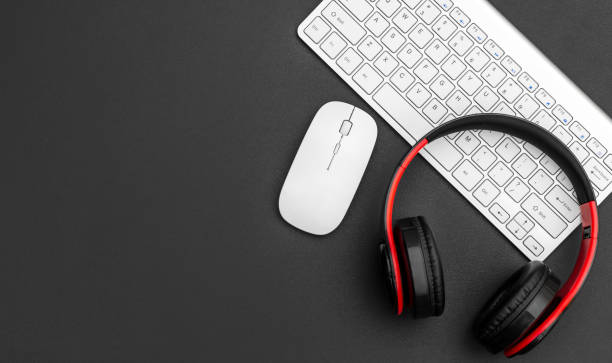 Headphones with computer keyboard and computer mouse on black. Top view. Space for text.