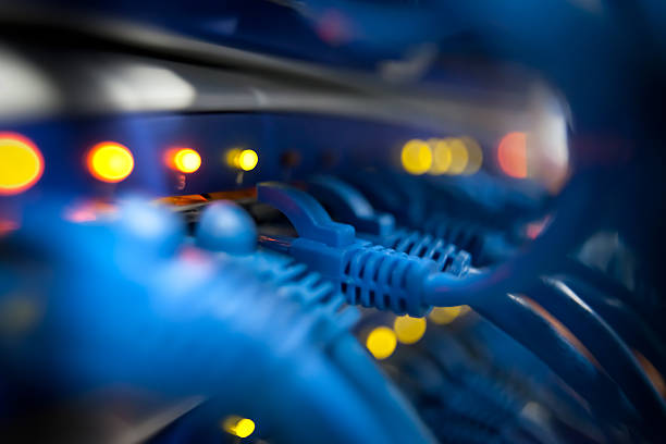 Selective focus closeup view of cables plugged into a server network panel with lights indicating activity. Photographed inside an equipment room.  Canon 5D MarkII. The file has been meticulously retouched in Photoshop eliminating dust and unwanted flaws. I have over 22 years experience as a photo retoucher.